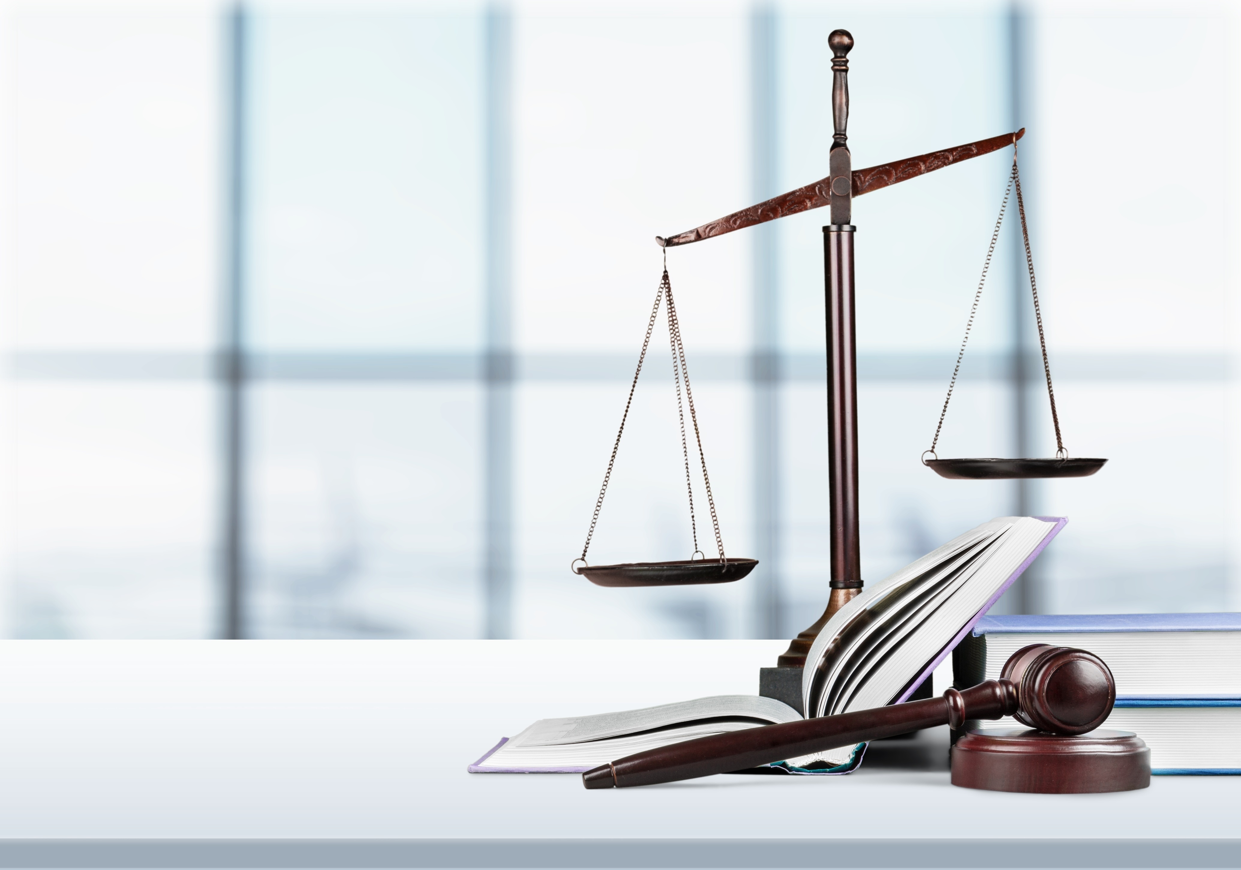 Scales of justice are pictured next to law case books and a gavel.