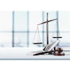Scales of justice are pictured next to law case books and a gavel.