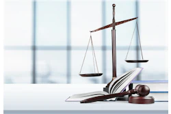 Scales of justice are pictured next to law case books and a gavel.