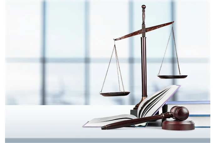 Scales of justice are pictured next to law case books and a gavel.