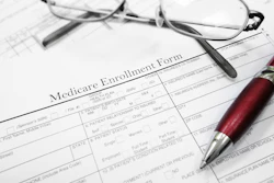 Medicare Enrollment Form with glasses and red pen on desk.