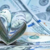 Rolled U.S. dollar bills shaped into a heart on scattered currency, symbolizing financial donation.