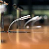 Professional microphones with flexible gooseneck stands on a wooden conference table.
