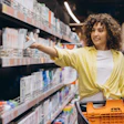 A woman shopper reaches for a box of toothpaste in a store.