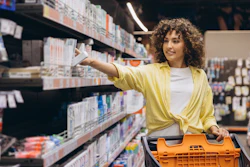 A woman shopper reaches for a box of toothpaste in a store.