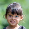A young girl smiles as the viewer.